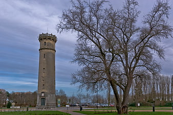 Historic stone tower and bare tree in Honfleur park