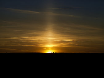 Golden sunset over dark silhouette landscape with sun rays