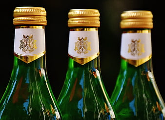 Close-up of three green wine bottles with gold foil