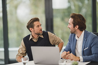 Two Business Men Discussing at Office Desk with Laptop