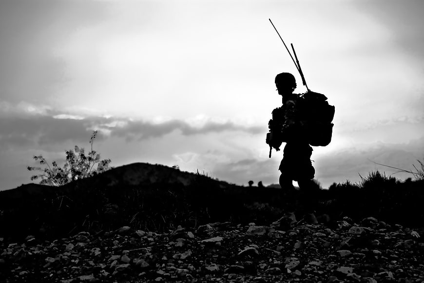 Silhouette of a soldier walking on a rocky hillside