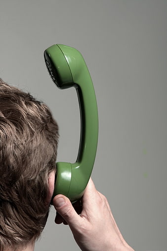 Man holding green retro telephone receiver to ear