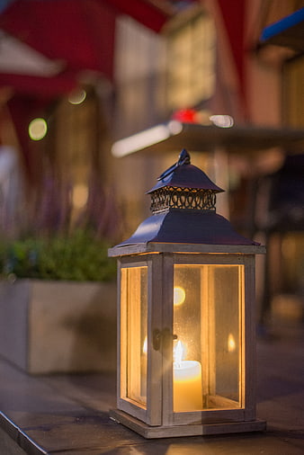 Glowing wooden lantern with candle on outdoor table at night