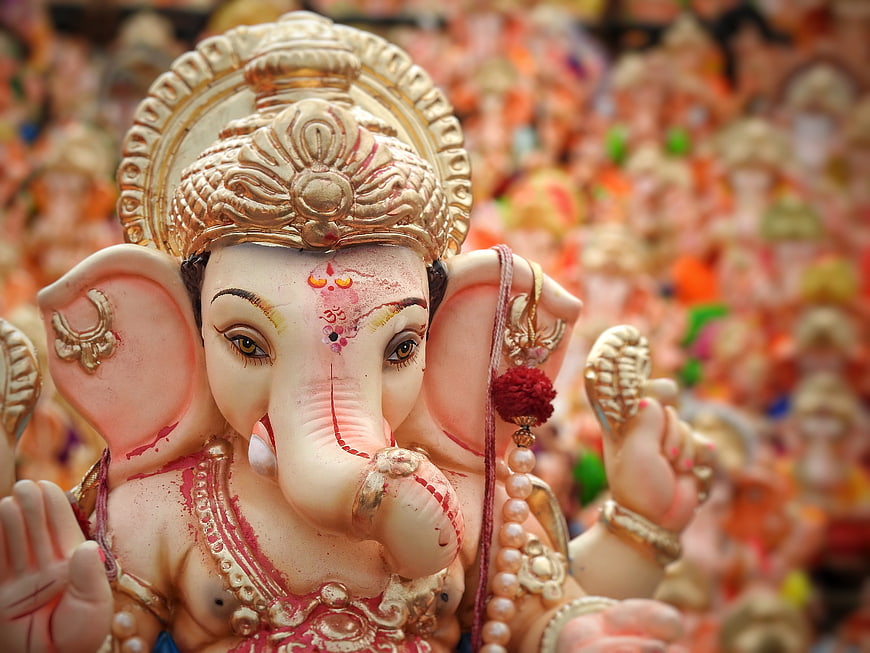 Close-up of ornate Ganesha idol with gold crown and red tilak