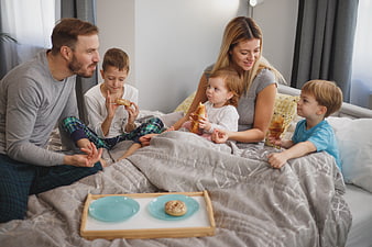 Happy family eating breakfast in bed together