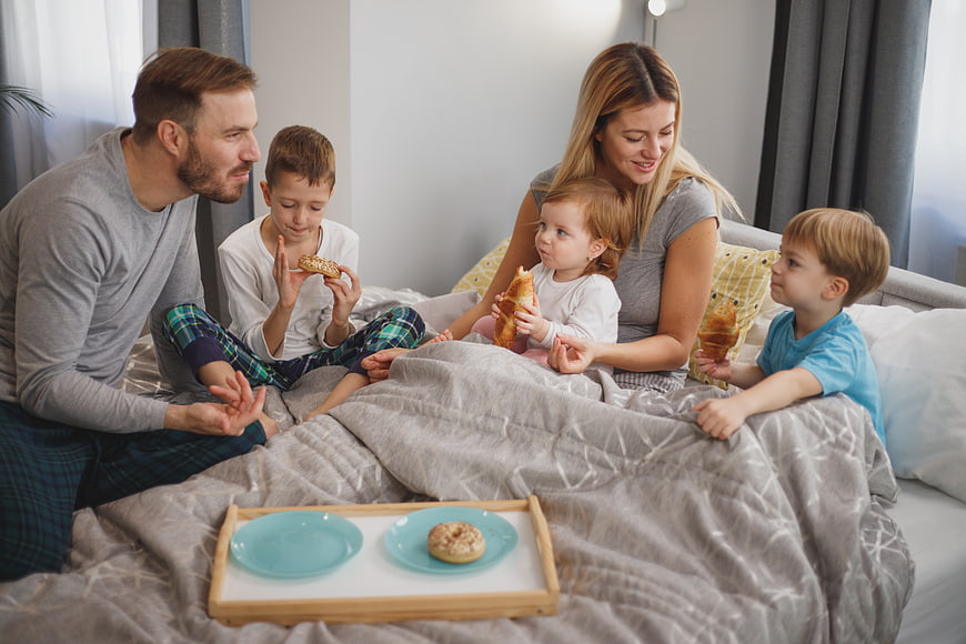Happy family eating breakfast in bed together