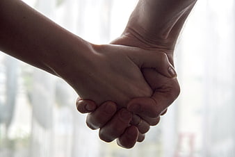 Close-up of two hands holding tightly together