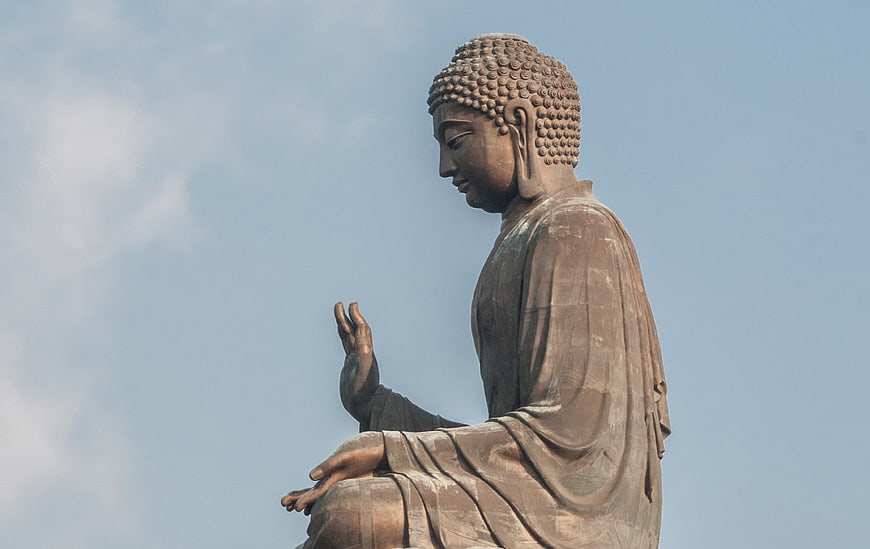 Side Profile of Giant Bronze Buddha Statue Against Blue Sky