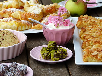Rustic wooden table spread with assorted pastries, cakes, and fresh apple