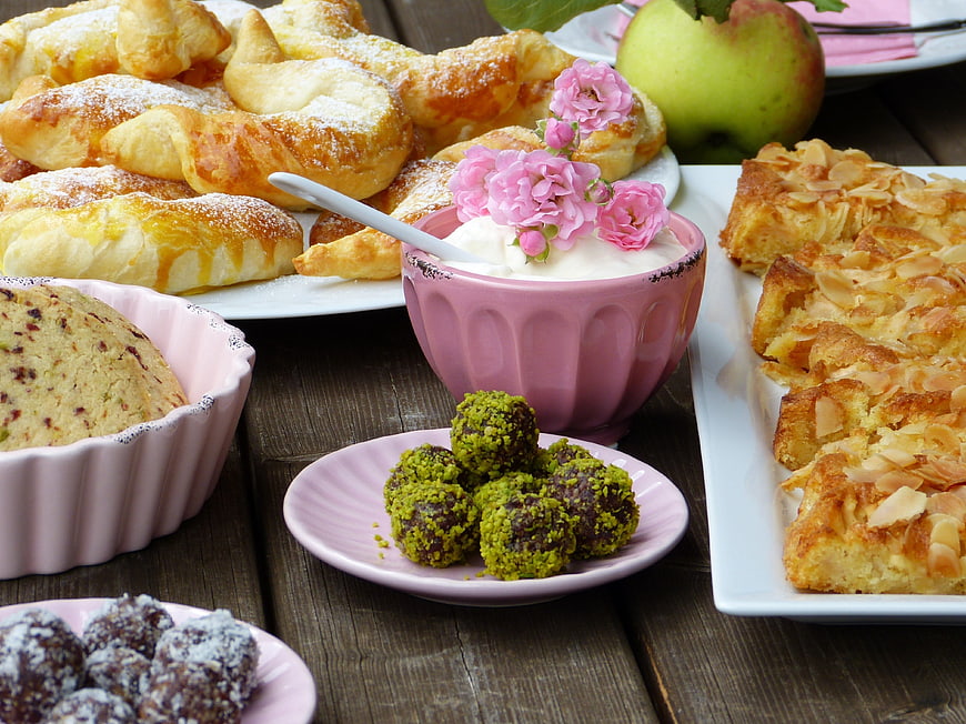 Rustic wooden table spread with assorted pastries, cakes, and fresh apple