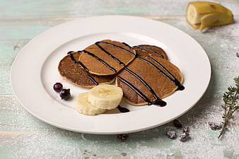Stack of chocolate pancakes with banana and chocolate drizzle