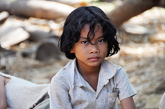 Portrait of a young boy with dark curly hair in a rural setting