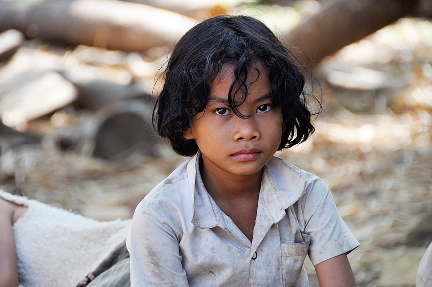 Portrait of a young boy with dark curly hair in a rural setting