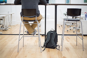 Person working at standing desk with backpack on floor