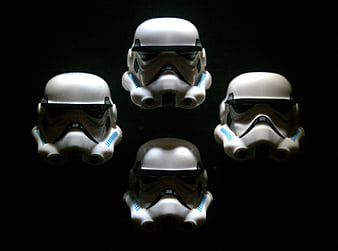 Four white stormtrooper helmets arranged on black background