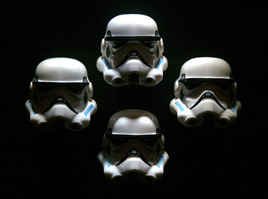 Four white stormtrooper helmets arranged on black background