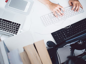 Overhead View of Hands Typing on Multiple Keyboards at Modern White Desk