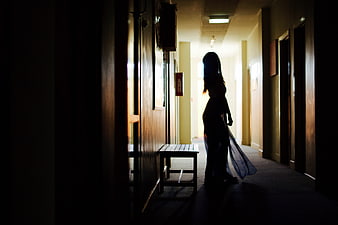 Silhouette of a woman standing in a dimly lit hallway