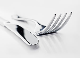 Close-up of shiny silver fork and knife on white background