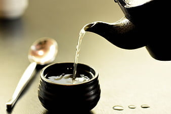 Pouring Tea from Teapot into Ceramic Cup