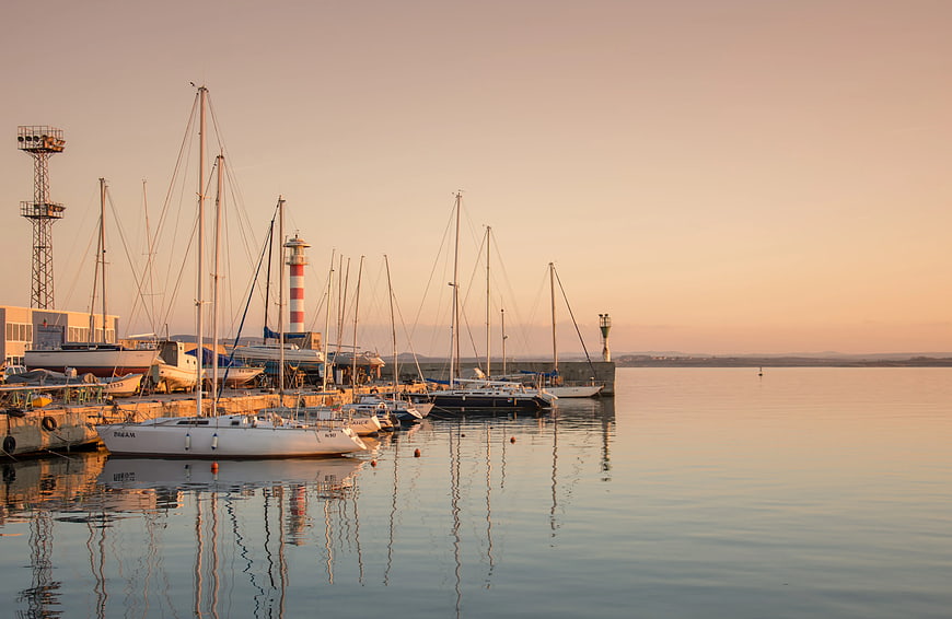 Sailboats docked in calm harbor at golden hour