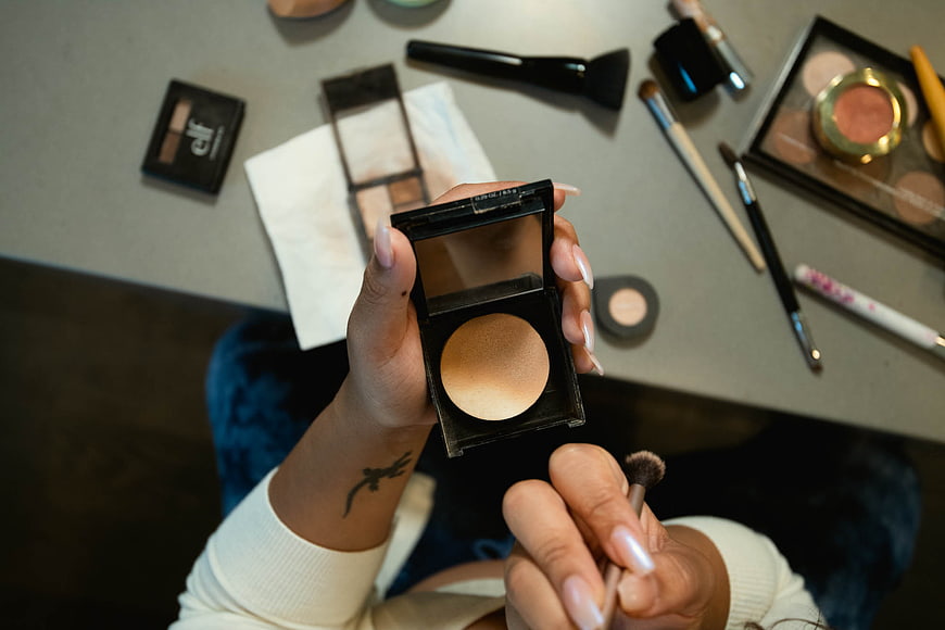Woman applying bronzer with makeup brush overhead view