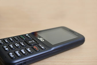 Black Jio feature phone on wooden table