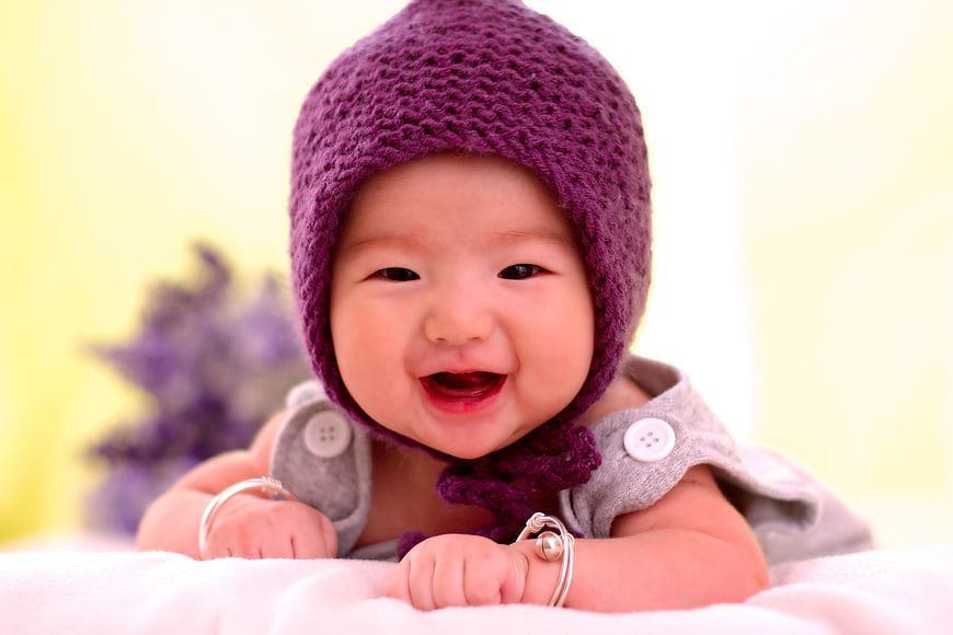 Smiling Baby Wearing Purple Knitted Hat and Silver Bracelets