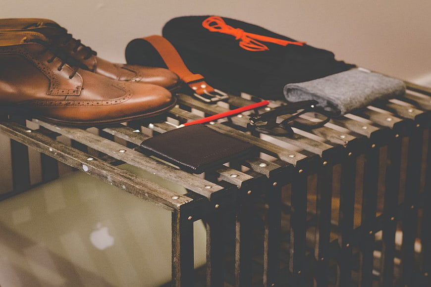Men's leather shoes, wallet, belt, and glasses on wooden crate