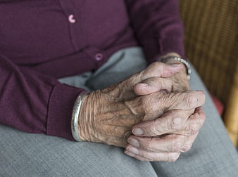 Close-up of elderly woman's wrinkled hands clasped in lap