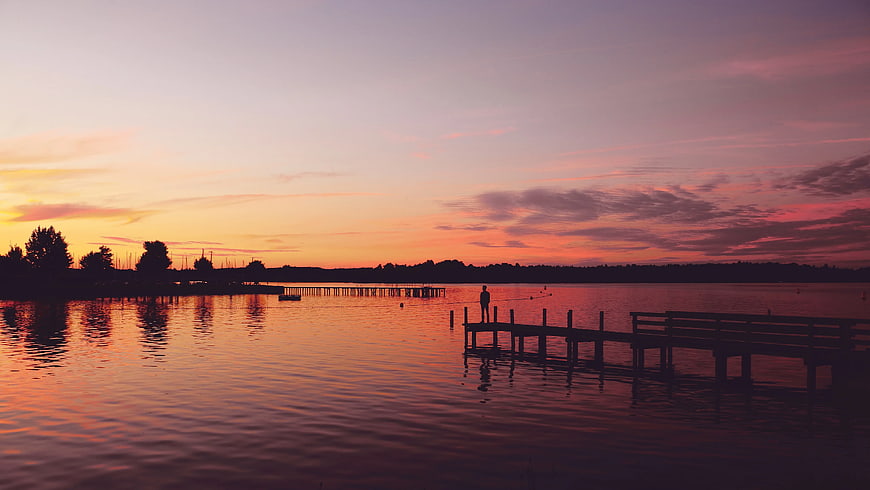 Silhouette of Man Fishing on Dock at Sunset