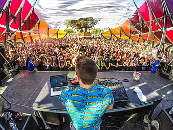 DJ performing live at outdoor music festival with crowd