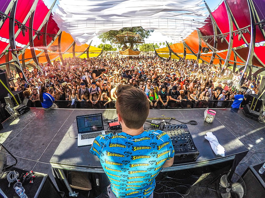 DJ performing live at outdoor music festival with crowd