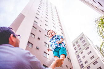 Happy Father Lifting Baby on Balcony with City View