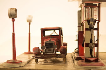 Vintage red die-cast car model at gas station