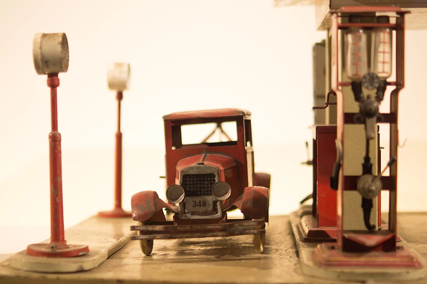Vintage red die-cast car model at gas station