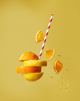 Fresh citrus fruit slices and straw floating on yellow background