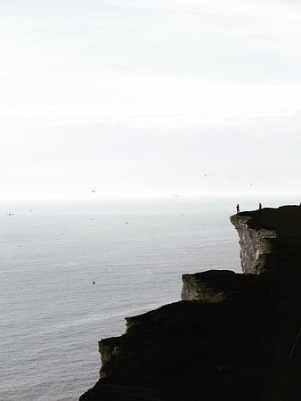 Silhouetted Figures on Dramatic Coastal Cliff Edge