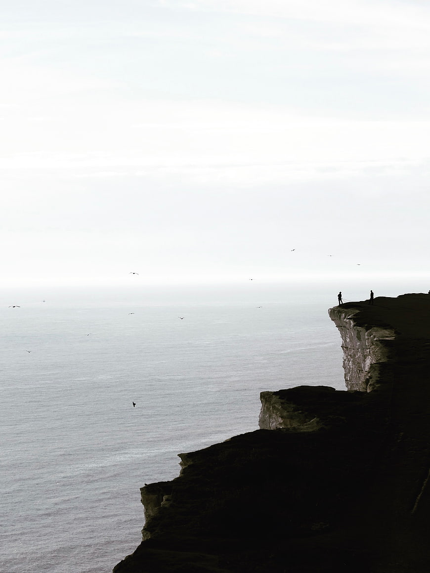 Silhouetted Figures on Dramatic Coastal Cliff Edge