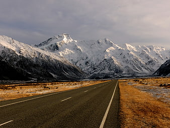 Empty Highway Leading to Snowy Mountain Peaks