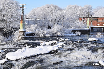 Snow-covered river rapids with industrial bridge and frosted trees
