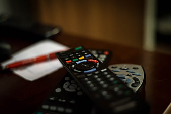 Stack of TV remote controls on wooden table