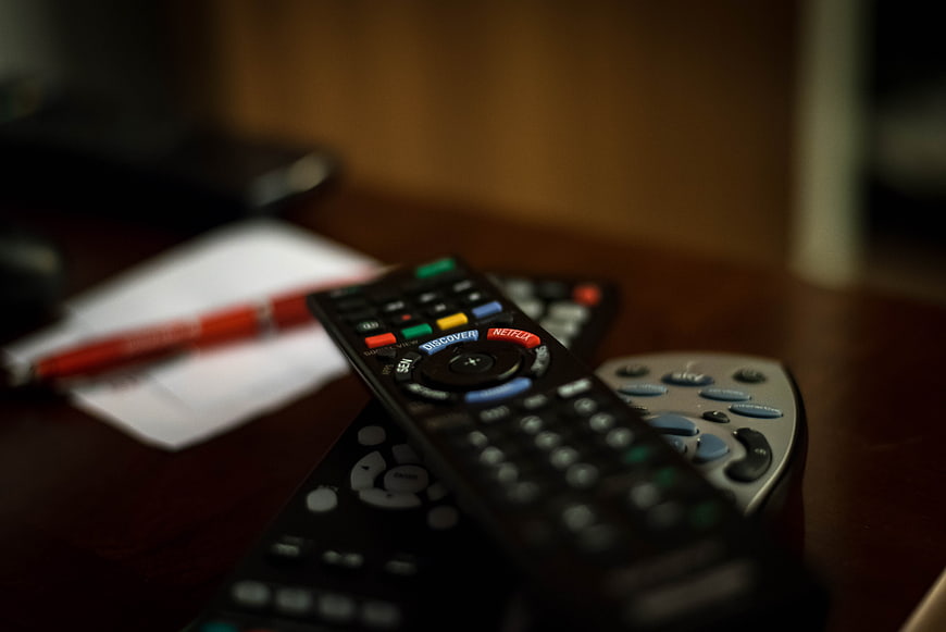 Stack of TV remote controls on wooden table