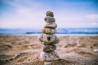 Stacked stones on sandy beach with ocean background