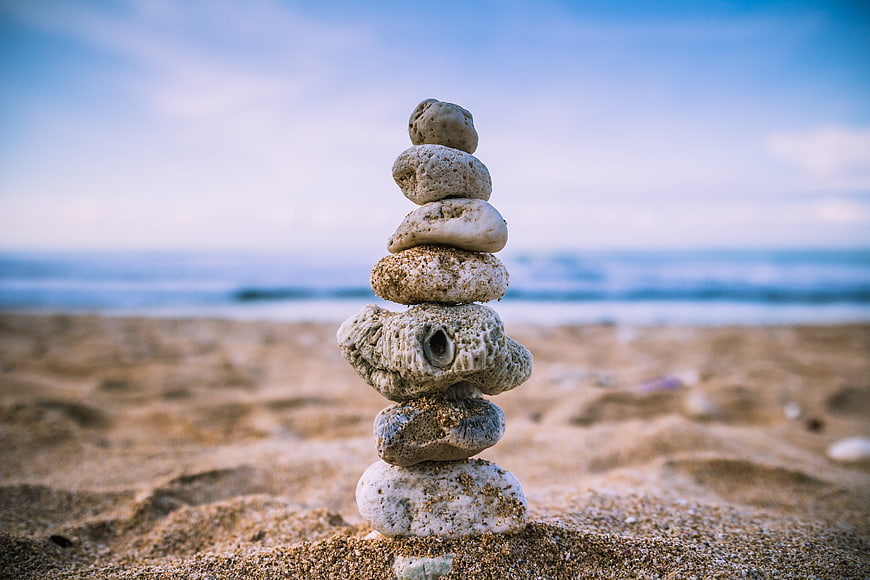 Stacked stones on sandy beach with ocean background