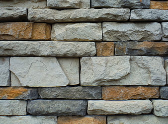 Textured stone wall with beige and orange rocks