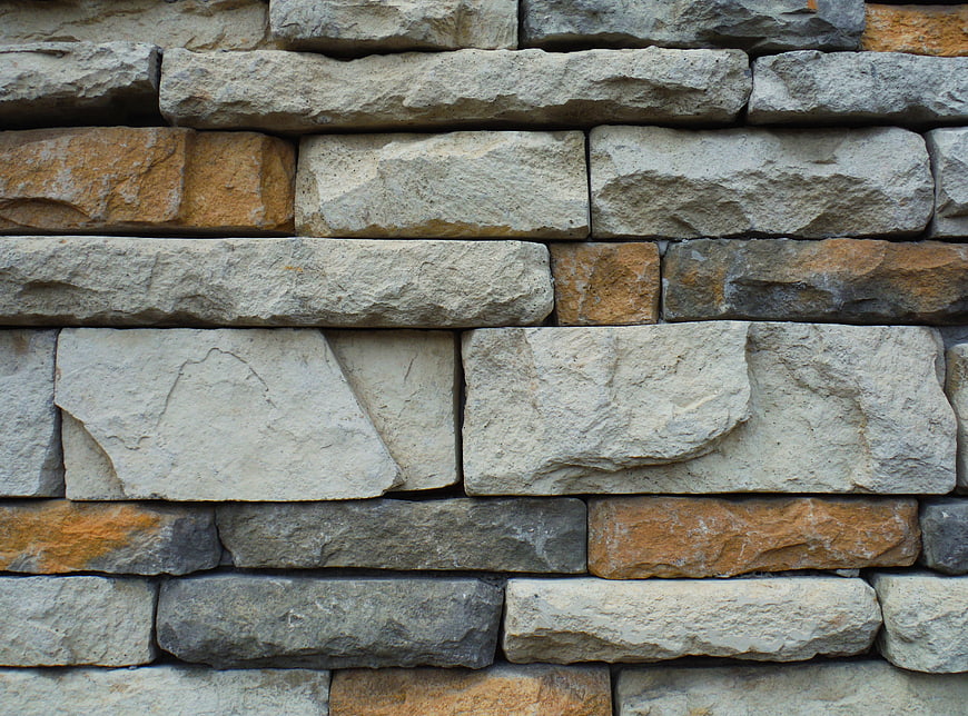 Textured stone wall with beige and orange rocks