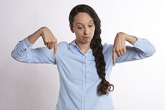 Woman in blue shirt pointing down with both hands