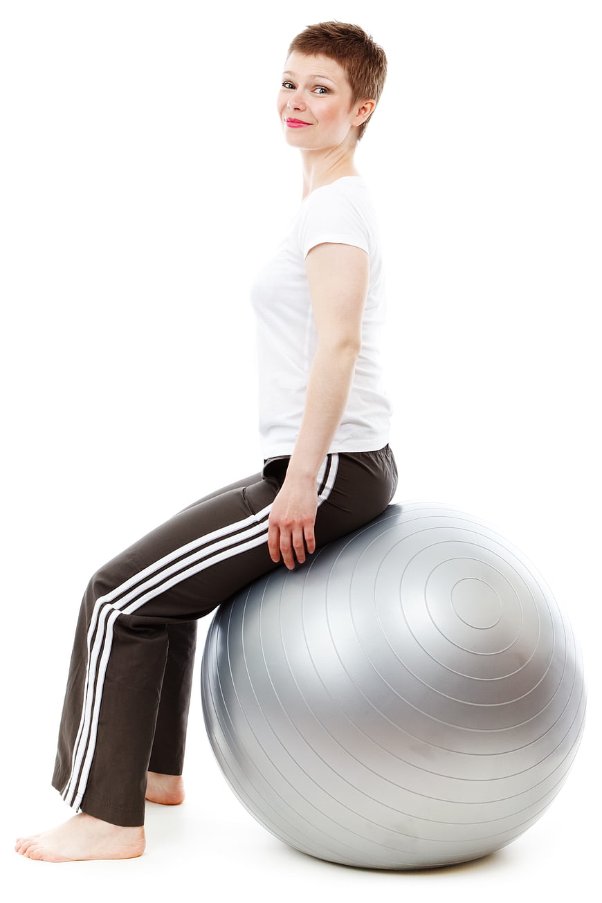 Woman sitting on silver exercise ball isolated on white