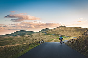 Cyclist Riding on Winding Mountain Road at Sunset